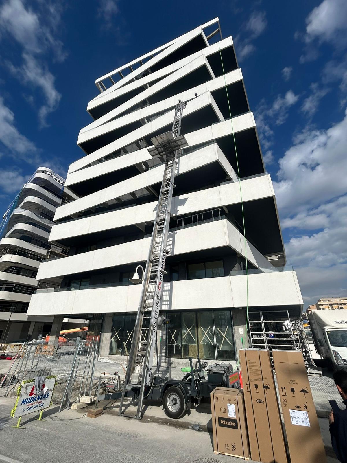 Plataforma elevadora subiendo electrodomésticos en obra nueva en Málaga
