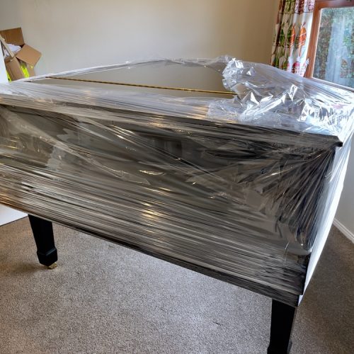 Glossy,Black,Grand,Piano,Partially,Covered,In,Plastic,Wrap,In